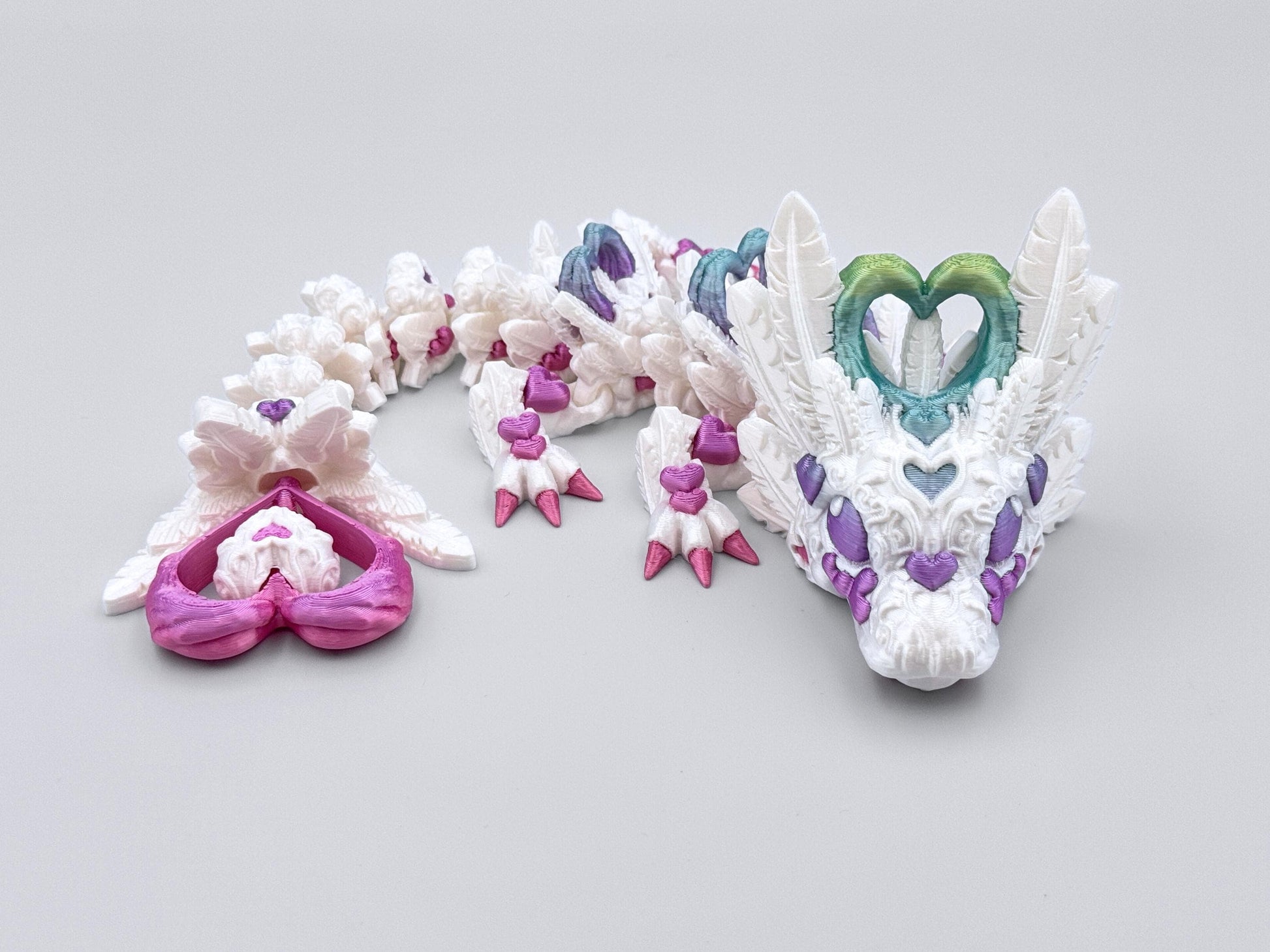 3D printed light heart dragon figurine with colorful heart accents in pink, purple and blue colors.