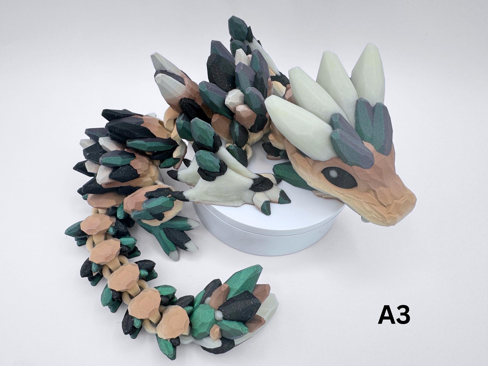 3D-printed Gemstone Baby Dragon fidget toy with an articulated body, featuring green, purple and black crystal scales. The segmented design allows flexible movement, while the intricate faceted details mimic the look of precious gemstones, creating a striking and mystical aesthetic.