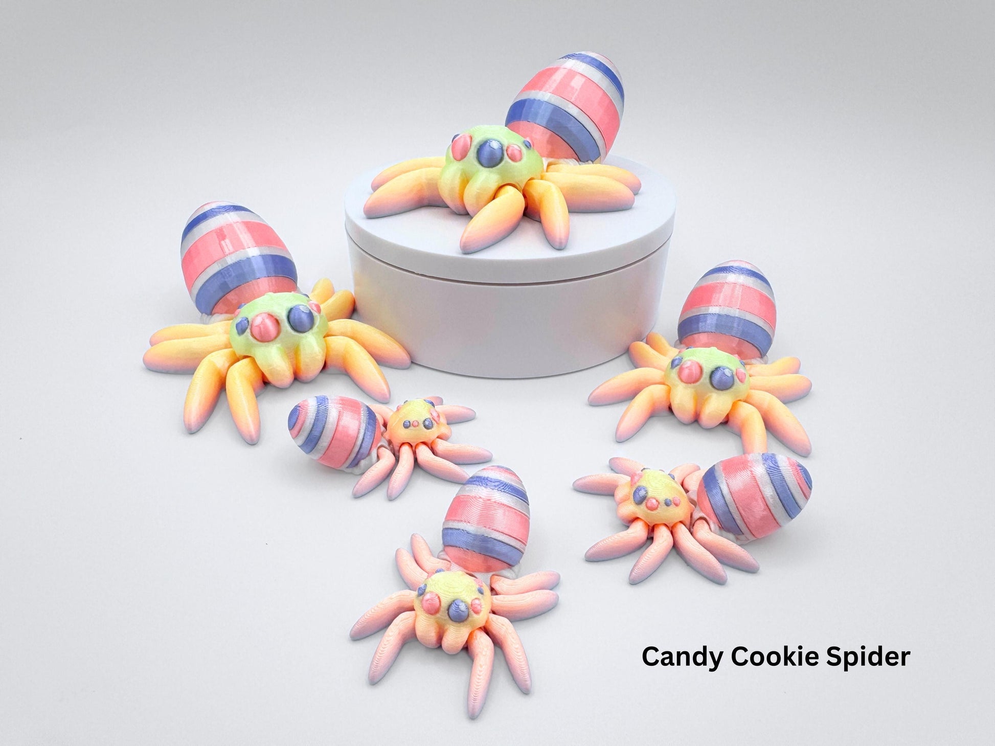 3D-printed Easter Egg Spider with a vibrant rainbow gradient body, seamlessly blending pastel tones. The egg on its back features bold pink, violet, and white stripes, adding a festive touch. Designed with an articulated structure and candy colored eyes, combining whimsy with intricate detailing.