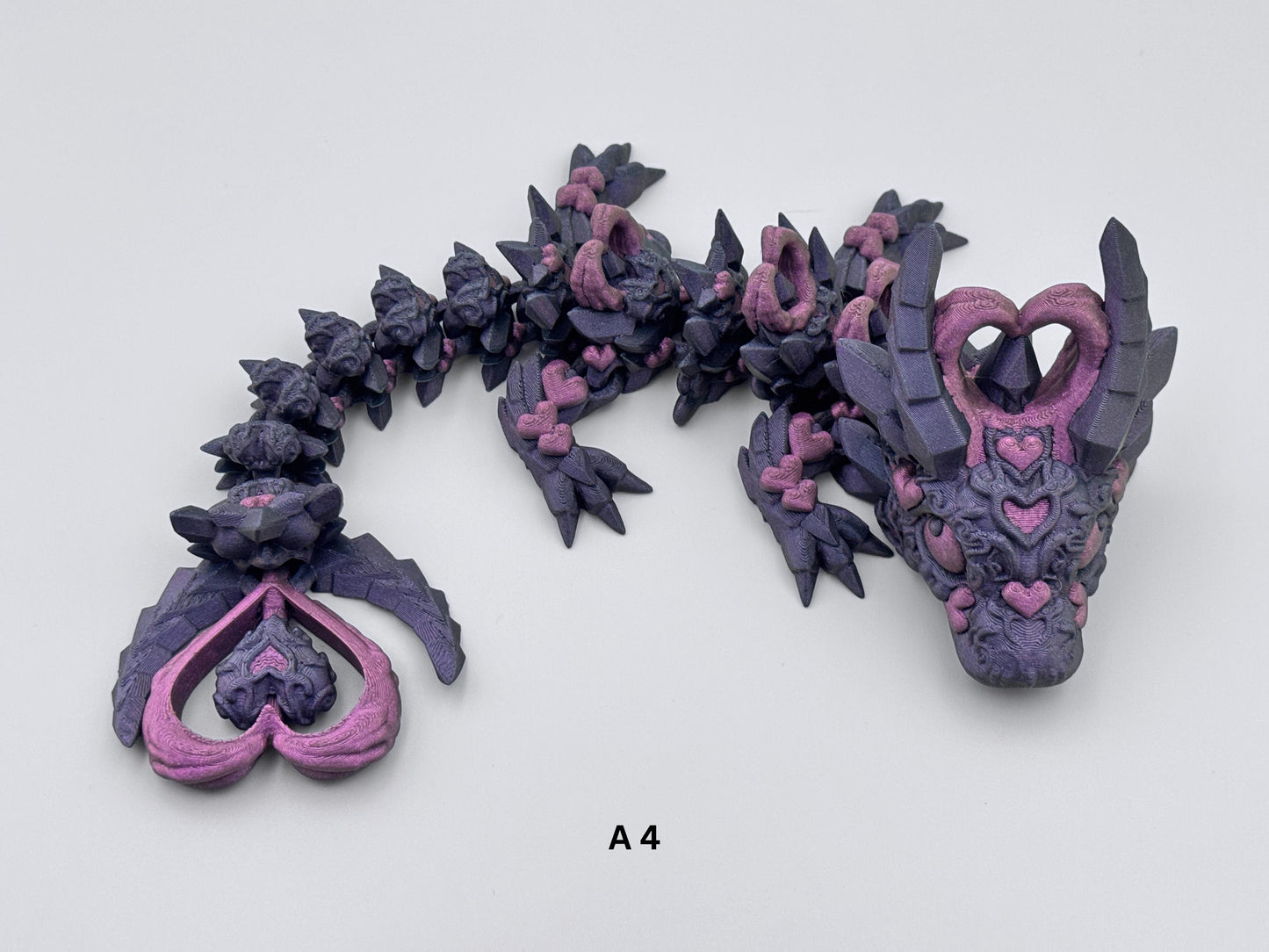 3D-printed Dark Heart Dragon fidget toy with an articulated blue-black body, adorned with intricate purple heart details. Features heart-shaped horns and tail tip, a segmented flexible design, and a fantasy-inspired aesthetic with elegant gothic accents.
