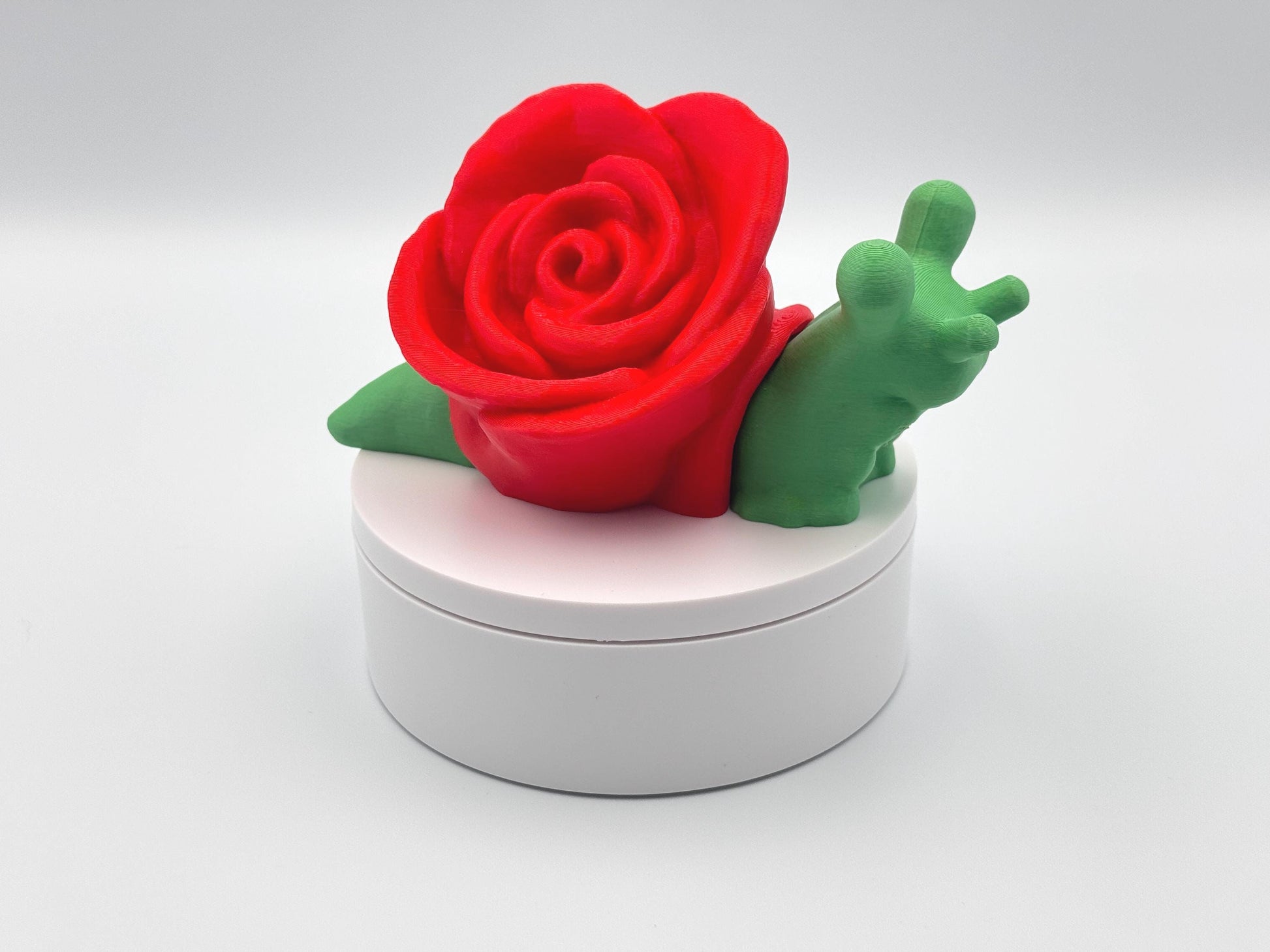 3D-printed articulated rose snail figurine with a vibrant red rose on its back and a bright green body. This cute and whimsical fidget toy is a perfect collectible, desk companion, or unique gift for nature and snail lovers.