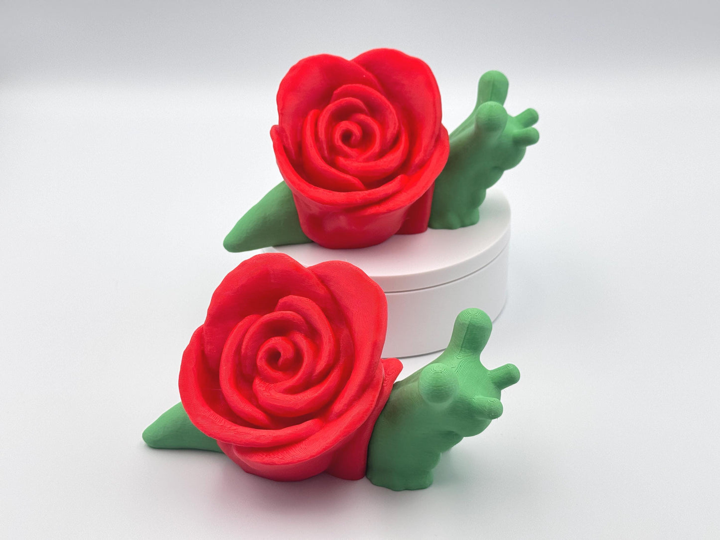 3D-printed articulated rose snail figurines with a vibrant red rose on their back and a bright green body. These cute and whimsical fidget toys are perfect collectible, desk companion or unique gift for nature and snail lovers.