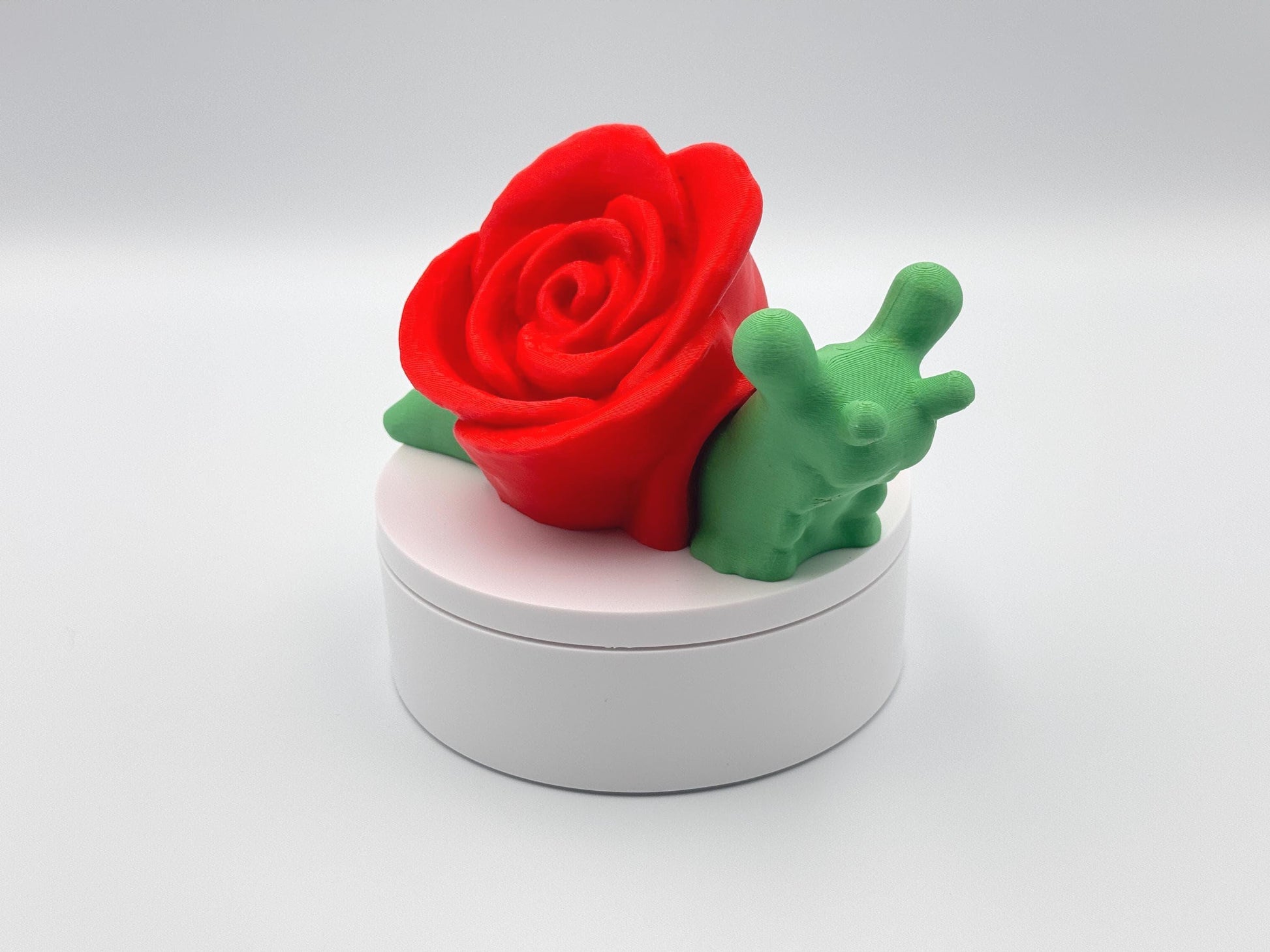 3D-printed articulated rose snail figurine with a vibrant red rose on its back and a bright green body. This cute and whimsical fidget toy is a perfect collectible, desk companion, or unique gift for nature and snail lovers.