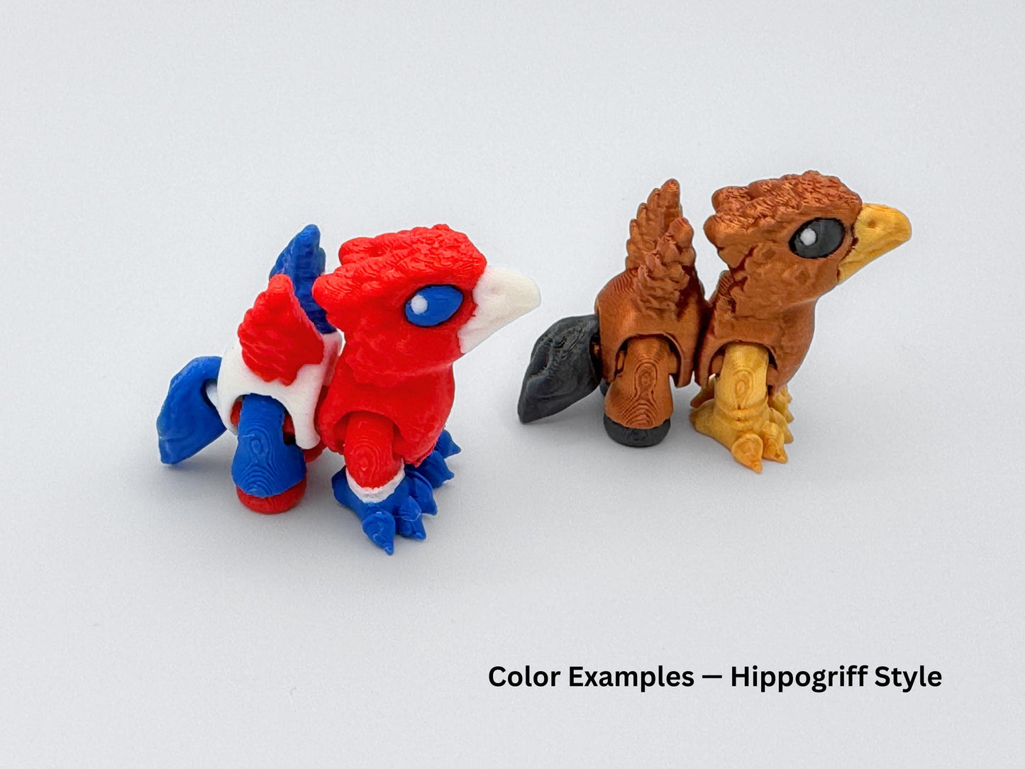 Two Hippogriff mini articulated animals shown side by side: one in patriotic red, white and blue, and the other in a brown and gold color scheme with black accents and feathered details.