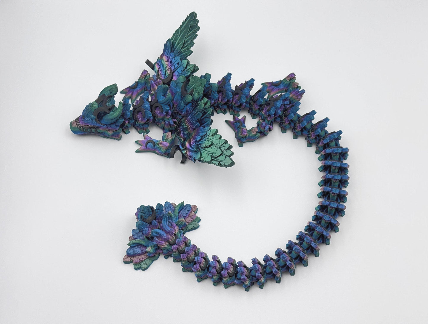 3D printed articulated Lunar Dragon with intricate feathered details, vibrant dark rainbow silk color palette blending shades of blue, green, and purple, and a fully flexible design. Perfect for fantasy collectors, unique decor, or imaginative play.