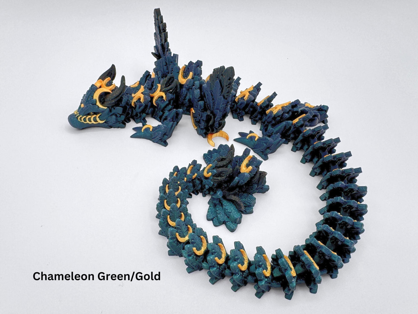 3D-printed articulated Lunar Dragon with intricate feathered details, a chameleon color palette blending deep emerald green with gold crescent moons and shimmering black accents. Features a fully flexible segmented design, making it perfect for fantasy collectors, unique decor, or imaginative play.