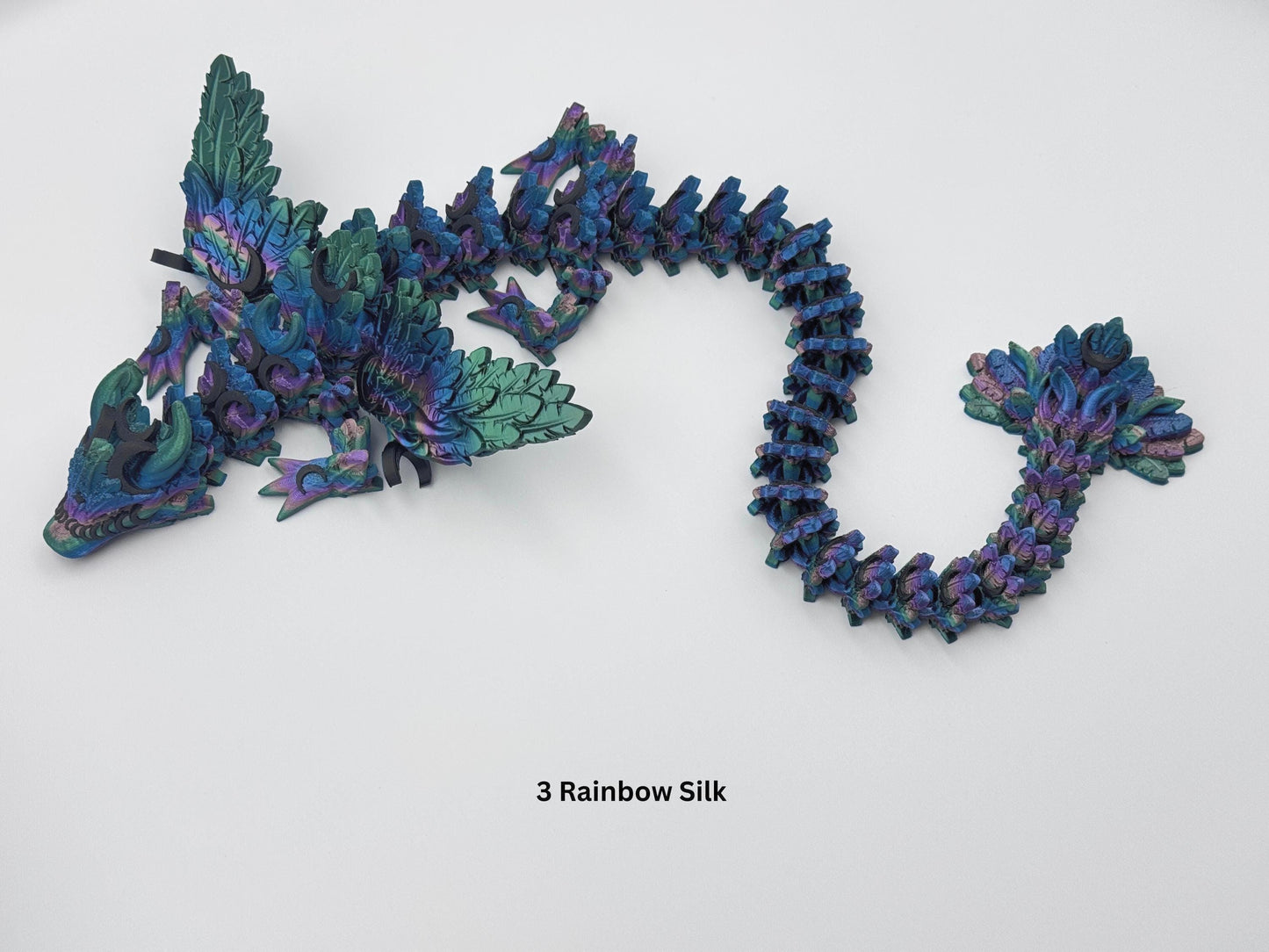 3D printed articulated Lunar Dragon with intricate feathered details, vibrant dark rainbow silk color palette blending shades of blue, green, and purple, and a fully flexible design. Perfect for fantasy collectors, unique decor, or imaginative play.
